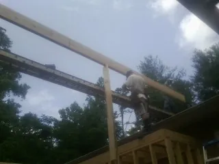 Carpenter setting a ridge beam over a new addition frame — Ice Dam Removal by Roofing Brothers in Retsof