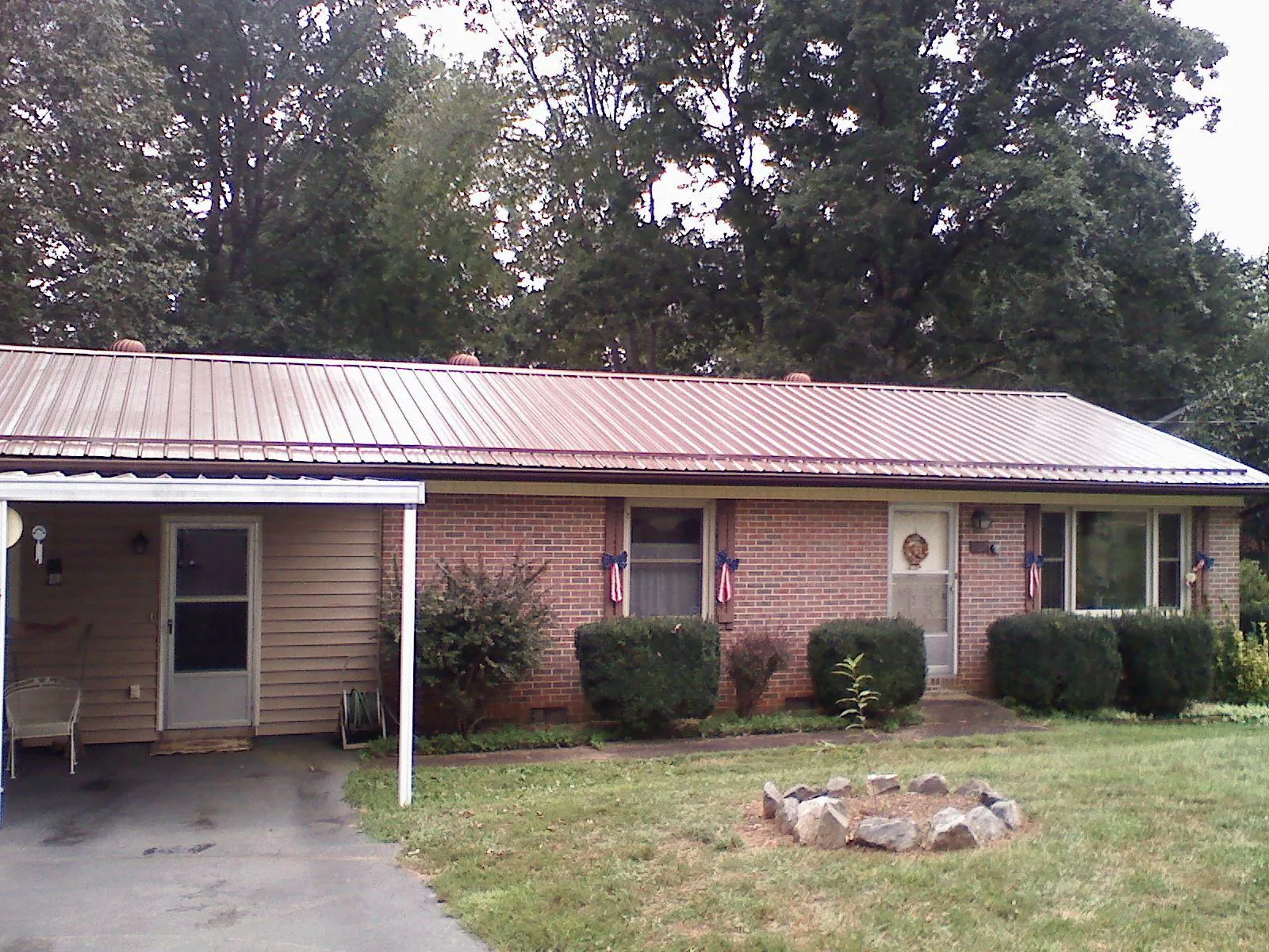 Bronze metal roof and carport on a brick ranch home — Roof Repair work by our crew in Retsof